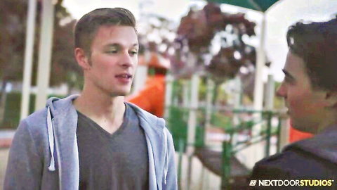 Two young athletic white guys in hoodies talking closely at outdoor playground in gay porn teaser