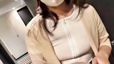 Asian woman in face mask wearing open beige cardigan teasing in hotel hallway