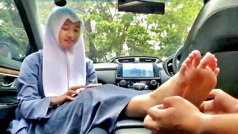 Hijab Asian woman getting foot massage in car, amateur style