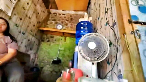 Asian amateur woman in casual clothes teasing in cozy room, fan blowing