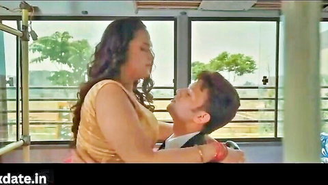 Busty Indian woman in gold top passionately embraces young man in bus