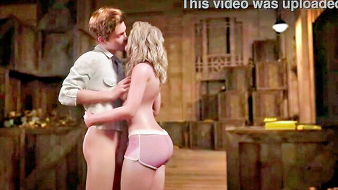 Blonde woman topless in pink shorts embraced by redhead man, hot intimate moment