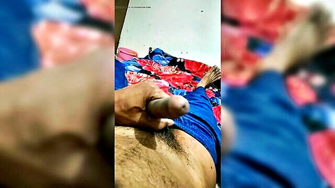 Brown-skinned Indian man stroking his erect cock with handjob on colorful bed