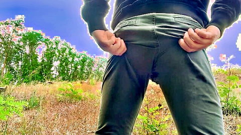 Skinny young guy flashing bare ass cheeks pulling down grey pants in public field