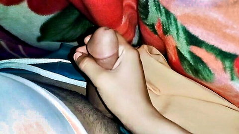 Brown hand gripping thick erect Pakistani cock in closeup handjob on floral bed