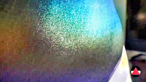 Close-up of shiny, multicolored spray on leotard-covered curvy hip