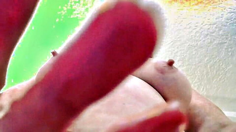 Busty mature woman pinching erect pink nipple with red nailed thumb closeup