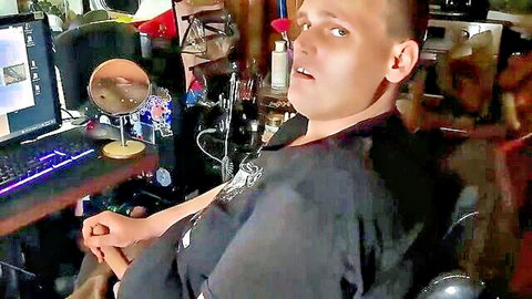 Amateur guy in black shirt sits at cluttered computer desk staring at mirror webcam style
