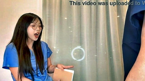 Young Asian nurse in glasses with long black hair gasps mouth open holding folder in blue scrubs