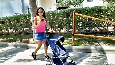 Abella Anderson in pink top and denim mini skirt pushing stroller outdoors