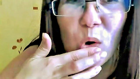 Mature woman in glasses opens mouth wide with hand spreading lips teasing blowjob