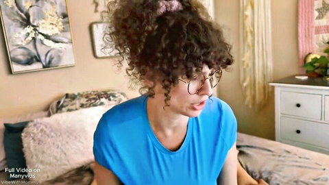 Curly haired MILF in glasses exposes big tits pulling down blue top on bed