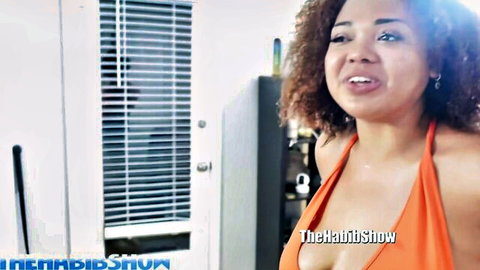 Mulatto Thickjawn in low-cut orange dress showing cleavage