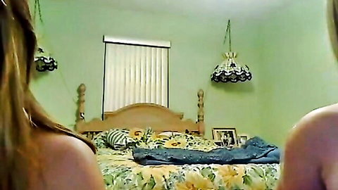 Two topless blondes with bare backs kneeling on floral bed facing girl in yellow top amateur webcam