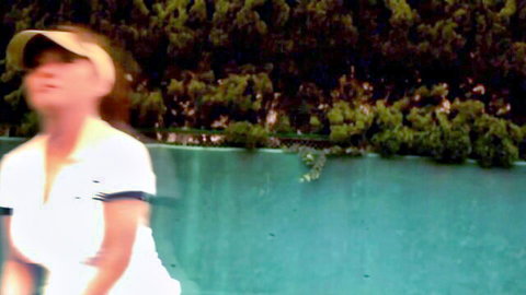 Sporty Asian woman in white polo and visor by poolside tennis court