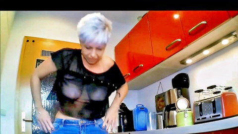 Blonde MILF teases big tits through sheer black top in tight jeans kitchen POV