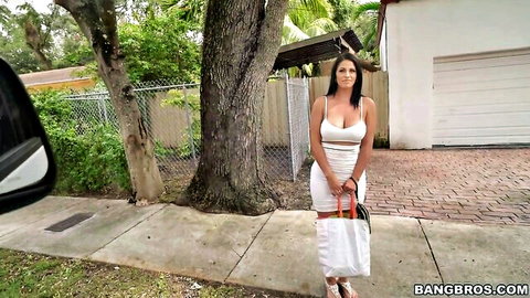 Brunette MILF in tight white dress shows off big tits holding purse outdoors