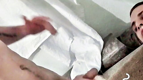 Young tattooed muscular guy strokes his hard erect cock on bed solo
