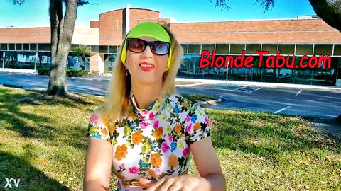 Smiling blonde MILF in floral top and green sunglasses poses outdoors teasing for taboo fun