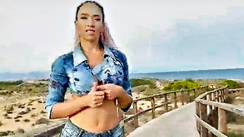 Sexy fit mixed babe in cropped blue top showing cleavage and abs on beach boardwalk