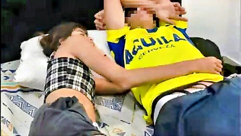 Step-sister in checkered crop top pinned by man in yellow jersey on bed