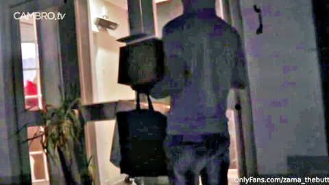 Ebony man in gray shirt and jeans holding bag entering doorway in amateur video