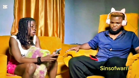 Black girlfriend in cat ears and pink mini skirt flirts with boyfriend on couch holding phones