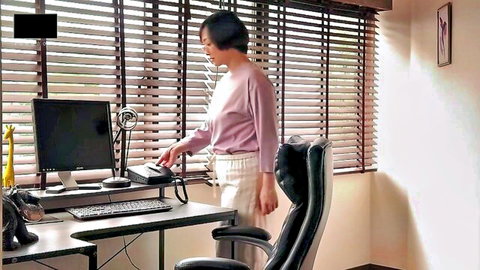 Japanese MILF in pink blouse and pants, standing by desk in JAV office scene