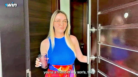 Blonde MILF mom in blue top holds drink asking if you're her son's friend at door