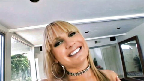 Tanned blonde MILF with big tits smiling topless wearing choker necklace POV