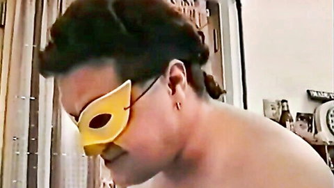 Shirtless man in yellow masquerade mask side profile showing bare chest and neck