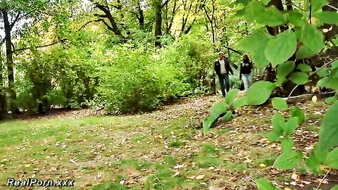 Leather-clad couple walks hand-in-hand through green forest outdoors