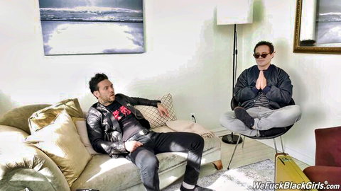 Two clothed Asian men lounge casually on sofa and chair in modern living room