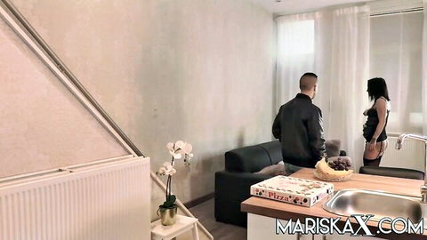 Brunette in black lingerie teases with bananas on hip in kitchen near pizza box
