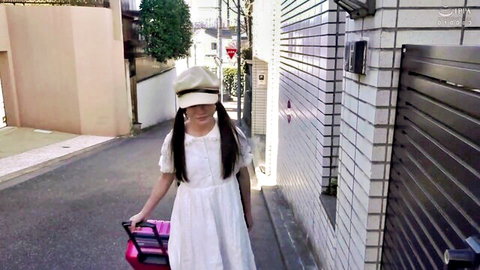 Cute tiny Japanese niece in white lolita dress with suitcase on street