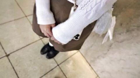 Cute Asian schoolgirl in white sweater and brown skirt, innocent standing pose