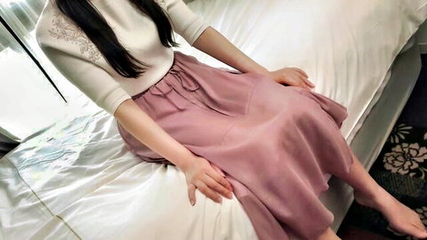 Cute Asian girl in white lace top and pink skirt sitting on bed, long black hair
