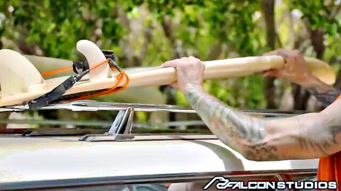 Alpha Wolfe with surfboard on van, tattooed arm, Falcon Studios gay scene