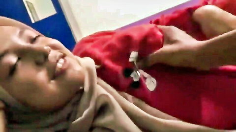 Smiling Asian woman in hijab with nipple clamps, man fondling breasts
