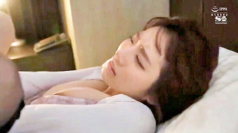 Asian woman in open blouse revealing cleavage, lying asleep on bed