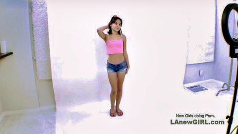 Skinny Asian teen in pink crop top and denim shorts posing in studio