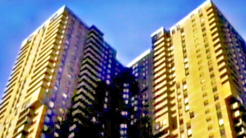 Two towering golden high-rise buildings against a vibrant blue sky in dramatic low-angle cityscape view