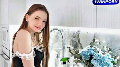 Sexy young brunette in off-shoulder lace top smiling teasingly in kitchen with blue flowers