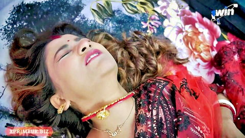 Sensual Indian woman in red saree lying on flower bed, teasing pose