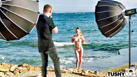 Fit blonde babe in tiny white micro bikini posing seductively on rocky beach during Tushy outdoor photoshoot