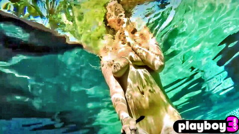 Nude curvy brunette babe covering big tits underwater in turquoise pool