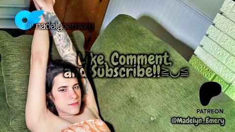 Tattooed trans babe with small tits teases raising arms in orange top on couch
