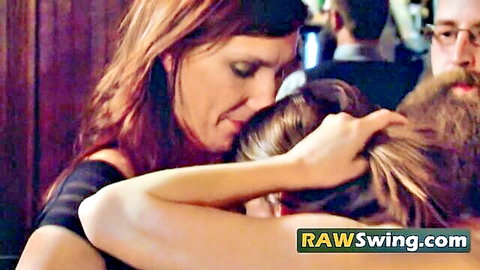 Redhead woman embracing blonde in swinger orgy group hug