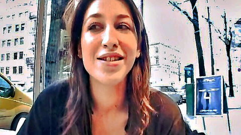 Brunette smiling outdoors, teasing surprise gift in urban scene