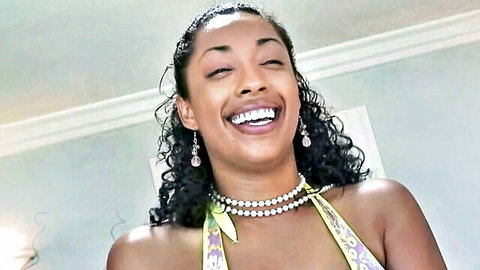 Smiling ebony beauty with long curls laughing in sexy yellow halter top and pearl necklace